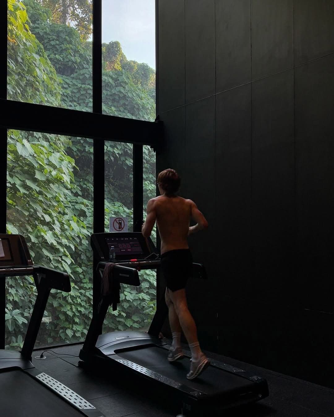 A man running on a treadmill beside a wall of greenery